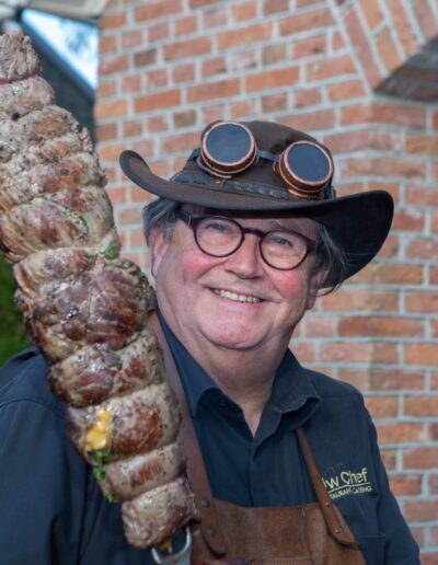 Grill Master Joop van Uw Chef Catering houdt grote spies met gegrild vlees vast. Foto: AbDonkerFotografie.